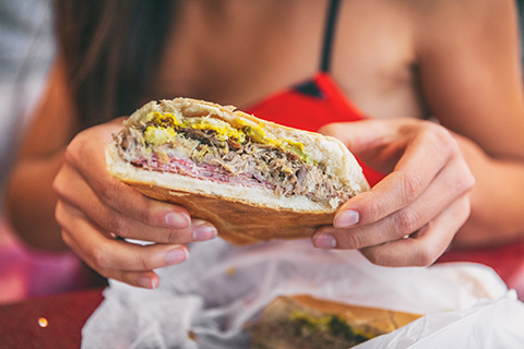 This is a stock photo from Shutterstock. This is a zoomed in image of a person holding a Cuban Sandwich.